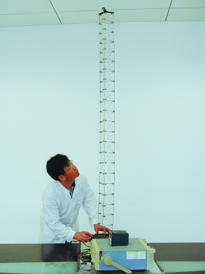 這是伸展開(kāi)的衛(wèi)星太陽(yáng)能電池用盤(pán)壓伸桿，20厘米長(zhǎng)螺旋狀的盤(pán)壓伸桿（右側(cè)小圖）打開(kāi)后能達(dá)2米長(zhǎng)（8月7日攝）。（新華社發(fā)）